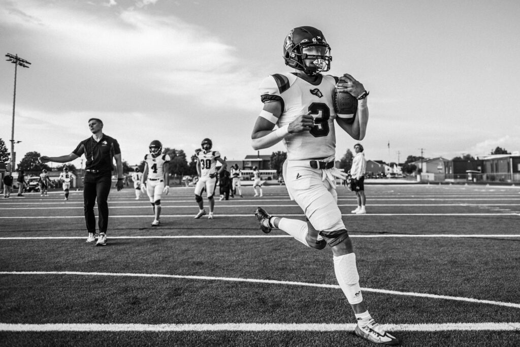 A football player running with the ball during pregame practice