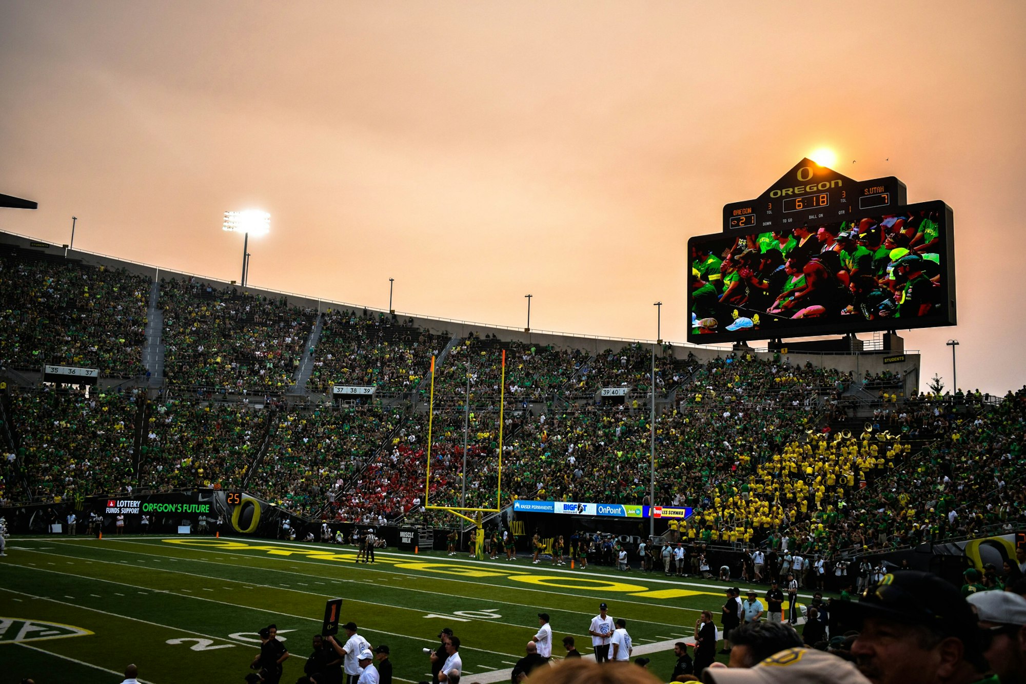A college football crowd in the stands at sunset
